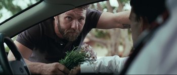 Movie still from “Animal Kingdom” (2010), directed by David Michôd – A man holding a bouquet of flowers in the back of a car; Close Up shot, Over the shoulder angle