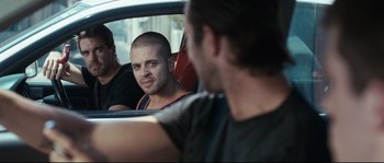 Movie still from “Animal Kingdom” (2010), directed by David Michôd – A man with a shaved head sitting in the passenger seat of a car; Medium shot, Over the shoulder angle