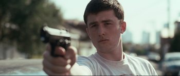 Movie still from “Animal Kingdom” (2010), directed by David Michôd – A young man holding a gun in his hand; Close Up shot, Low angle