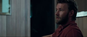 Movie still from “Animal Kingdom” (2010), directed by David Michôd – A man with a beard is sitting in front of a window at night; Close Up shot, Over the shoulder angle