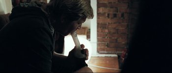 Movie still from “Animal Kingdom” (2010), directed by David Michôd – A man sitting on the floor holding a wii controller; Medium shot, Low angle