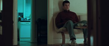Movie still from “Animal Kingdom” (2010), directed by David Michôd – A man sitting on a chair in a room; Medium shot, Low angle