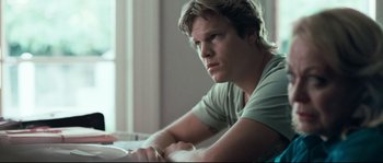 Movie still from “Animal Kingdom” (2010), directed by David Michôd – A man sitting at a table looking at the camera; Close Up shot, Low angle
