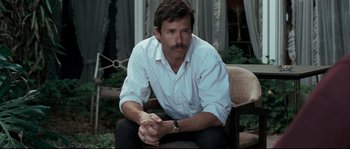 Movie still from “Animal Kingdom” (2010), directed by David Michôd – A man sitting in a chair with his hands crossed; Medium shot, Over the shoulder angle