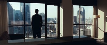 Movie still from “Animal Kingdom” (2010), directed by David Michôd – A man standing in front of an open window looking out at a city; Wide shot, Low angle
