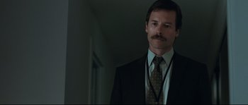 Movie still from “Animal Kingdom” (2010), directed by David Michôd – A man in a suit and tie standing in a room; Close Up shot, Over the shoulder angle
