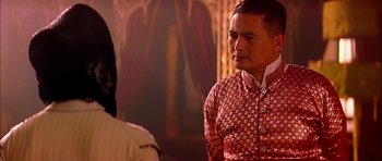 Movie still from “Anna and the King” (1999), directed by Andy Tennant – A man in a red shirt is standing in front of a painting; Medium shot, Over the shoulder angle