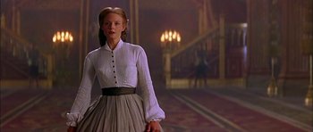 A woman in a white dress standing in front of a staircase