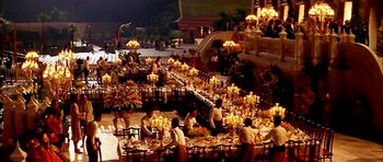 Movie still from “Anna and the King” (1999), directed by Andy Tennant – A group of people sitting around a table with many candles; Extreme Wide shot, High angle