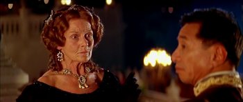 Movie still from “Anna and the King” (1999), directed by Andy Tennant – An older woman wearing a black dress and a gold necklace; Close Up shot, Over the shoulder angle