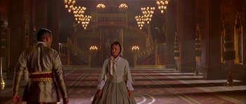 Movie still from “Anna and the King” (1999), directed by Andy Tennant – A woman standing in front of chandeliers in a room; Wide shot, Low angle
