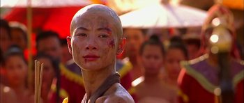 Movie still from “Anna and the King” (1999), directed by Andy Tennant – A person with a shaved head and a bunch of other people; Close Up shot, Over the shoulder angle