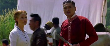 Movie still from “Anna and the King” (1999), directed by Andy Tennant – A man in a red shirt holding a sword; Medium shot, Low angle