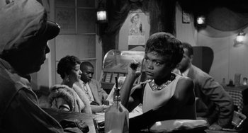 Movie still from “Anna Lucasta” (1958), directed by Arnold Laven – A black and white photo of a woman sitting at a table; Medium shot, Over the shoulder angle