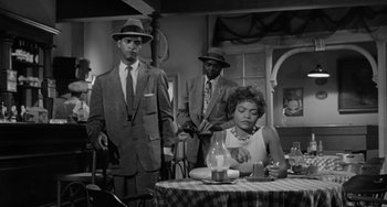 Movie still from “Anna Lucasta” (1958), directed by Arnold Laven – A group of people standing around a dining table; Medium shot, Low angle