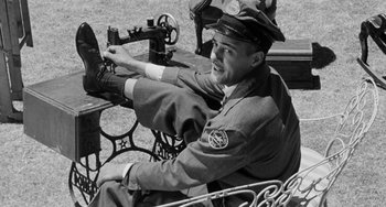 Movie still from “Anna Lucasta” (1958), directed by Arnold Laven – A man sitting on top of a bench wearing a hat; Medium shot, Low angle
