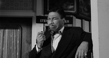 Movie still from “Anna Lucasta” (1958), directed by Arnold Laven – A man in a suit smoking a cigarette and holding a cell phone to his ear; Close Up shot, Low angle