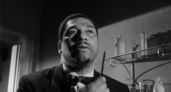 Movie still from “Anna Lucasta” (1958), directed by Arnold Laven – A black and white photo of a man in a suit holding a pen; Close Up shot, Low angle