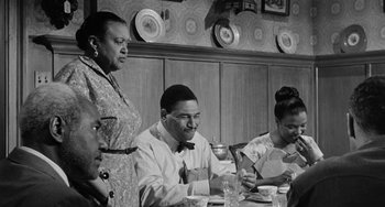 Movie still from “Anna Lucasta” (1958), directed by Arnold Laven – A group of people sitting at a dinner table; Medium shot, Over the shoulder angle