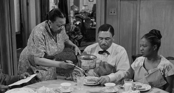 Movie still from “Anna Lucasta” (1958), directed by Arnold Laven – An old photo of two people at a dinner table; Medium shot, High angle