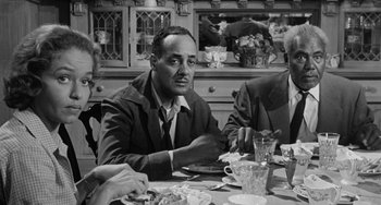 Movie still from “Anna Lucasta” (1958), directed by Arnold Laven – A man sitting at a table with a plate in front of him; Medium shot, Over the shoulder angle