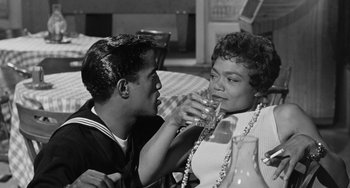 Movie still from “Anna Lucasta” (1958), directed by Arnold Laven – A man and a woman are drinking a glass of water; Medium shot, High angle