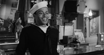 Movie still from “Anna Lucasta” (1958), directed by Arnold Laven – A man in a sailor's uniform smiles for the camera; Medium shot, Low angle