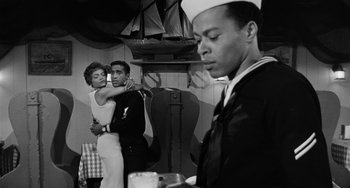 Movie still from “Anna Lucasta” (1958), directed by Arnold Laven – A man and a woman hug in front of a sailor; Medium shot, Over the shoulder angle