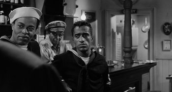 Movie still from “Anna Lucasta” (1958), directed by Arnold Laven – A man sitting in front of another man in front of a mirror; Medium shot, Over the shoulder angle