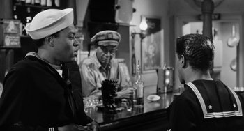 Movie still from “Anna Lucasta” (1958), directed by Arnold Laven – A black and white photo of three men sitting at a bar; Medium shot, Over the shoulder angle