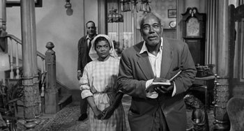Movie still from “Anna Lucasta” (1958), directed by Arnold Laven – An old photo of a man and a woman and another man; Medium shot, Low angle