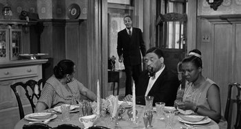 Movie still from “Anna Lucasta” (1958), directed by Arnold Laven – A man in a suit standing at a dinner table; Medium shot, High angle