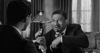Movie still from “Anna Lucasta” (1958), directed by Arnold Laven – An older man in a suit and tie holding a pipe; Close Up shot, Over the shoulder angle