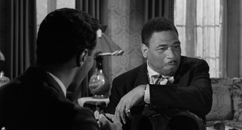 Movie still from “Anna Lucasta” (1958), directed by Arnold Laven – A man in a suit and tie sitting next to another man in a suit and tie; Close Up shot, Over the shoulder angle
