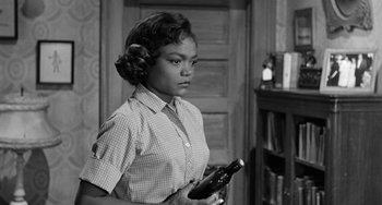 Movie still from “Anna Lucasta” (1958), directed by Arnold Laven – A black and white photo of a woman holding a wine bottle; Medium shot, Over the shoulder angle