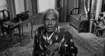 Movie still from “Anna Lucasta” (1958), directed by Arnold Laven – An older man sitting in a living room; Medium shot, High angle