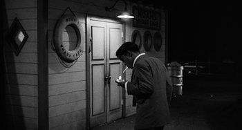 Movie still from “Anna Lucasta” (1958), directed by Arnold Laven – A black and white photo of a man smoking a cigarette; Medium shot, High angle