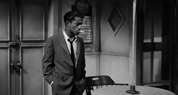 Movie still from “Anna Lucasta” (1958), directed by Arnold Laven – A black and white photo of a man in a suit and tie; Medium shot, Over the shoulder angle