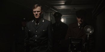 Movie still from “Dark” (2017), created by Baran bo Odar – A group of men in uniform standing next to each other; Medium shot, Over the shoulder angle