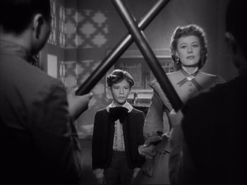 Movie still from “Anna and the King of Siam” (1946), directed by John Cromwell – A man and a woman are standing in front of a boy; Medium shot, Over the shoulder angle