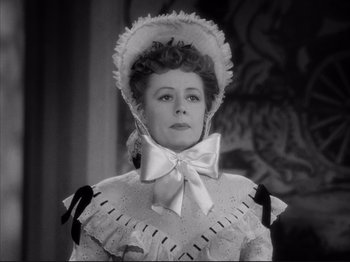 Movie still from “Anna and the King of Siam” (1946), directed by John Cromwell – An old photo of a woman wearing a hat and a bow tie; Close Up shot, Over the shoulder angle
