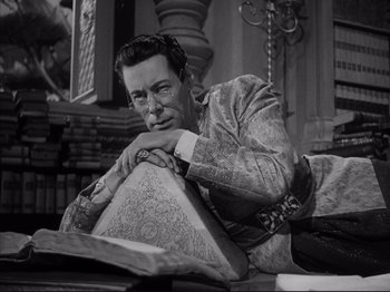 Movie still from “Anna and the King of Siam” (1946), directed by John Cromwell – A black and white photo of a man sitting at a table; Medium shot, High angle