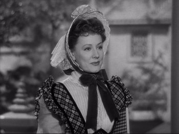 Movie still from “Anna and the King of Siam” (1946), directed by John Cromwell – An older woman wearing a hat and a plaid dress; Close Up shot, Over the shoulder angle