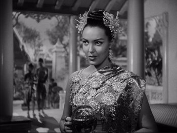 Movie still from “Anna and the King of Siam” (1946), directed by John Cromwell – A black and white photo of a woman holding a drink; Medium shot, Over the shoulder angle