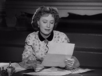 Movie still from “Anna and the King of Siam” (1946), directed by John Cromwell – An older woman sitting at a table reading a piece of paper; Close Up shot, Over the shoulder angle