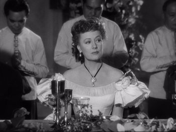 Movie still from “Anna and the King of Siam” (1946), directed by John Cromwell – An old photo of a woman sitting at a table with a glass of wine; Medium shot, Over the shoulder angle