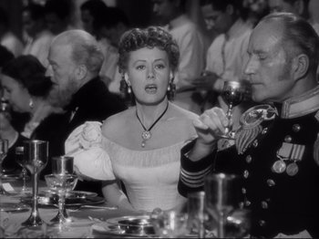 Movie still from “Anna and the King of Siam” (1946), directed by John Cromwell – A woman in a white dress sitting at a dinner table; Medium shot, Over the shoulder angle