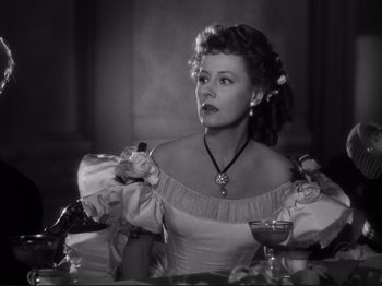 Movie still from “Anna and the King of Siam” (1946), directed by John Cromwell – An old photo of a woman sitting at a table with a drink; Medium shot, Over the shoulder angle