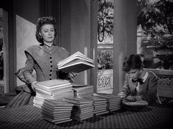 Movie still from “Anna and the King of Siam” (1946), directed by John Cromwell – Two women sitting at a table with a stack of books; Medium shot, High angle