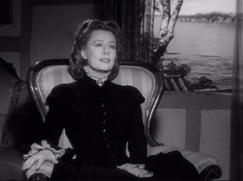 Movie still from “Anna and the King of Siam” (1946), directed by John Cromwell – An older woman sitting in a chair in front of a painting; Medium shot, Over the shoulder angle